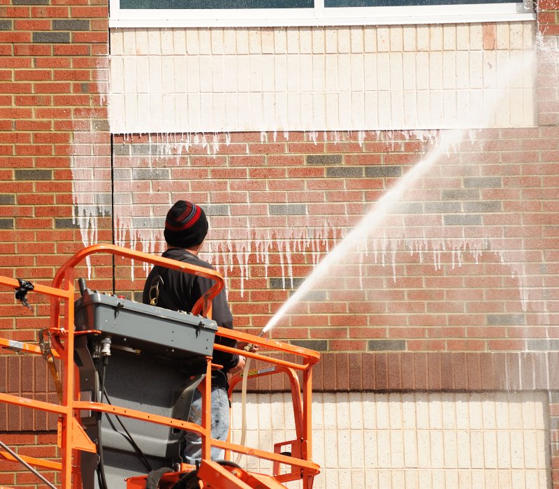 outdoor worker cleaning the exterior wall of building through pressure water