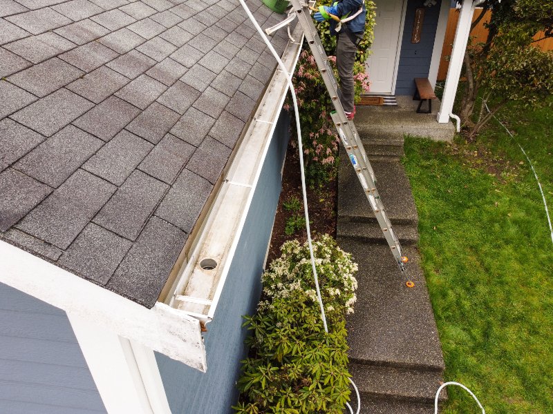 worker cleaning house gutter from leaves and dirt