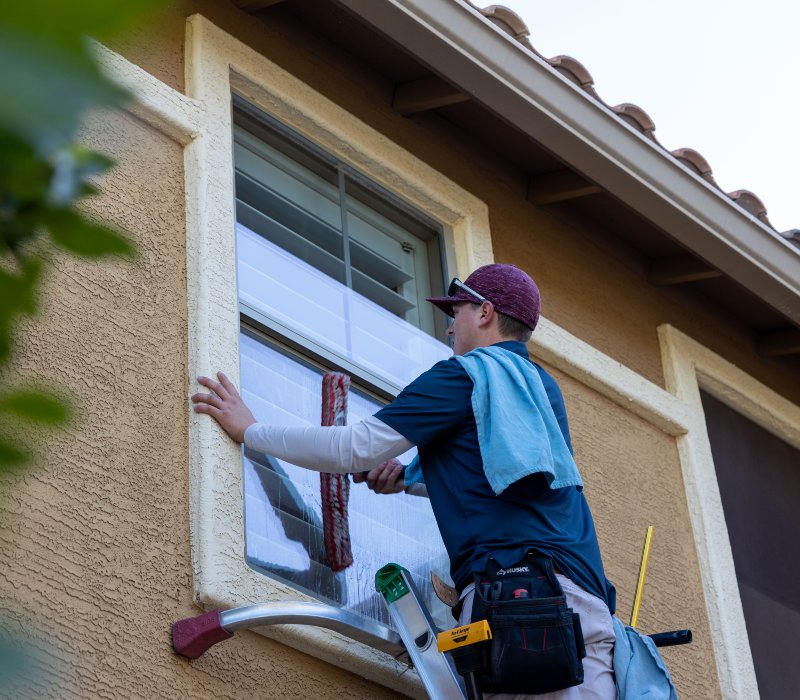 A professional window cleaner using a squeegee to clean a window